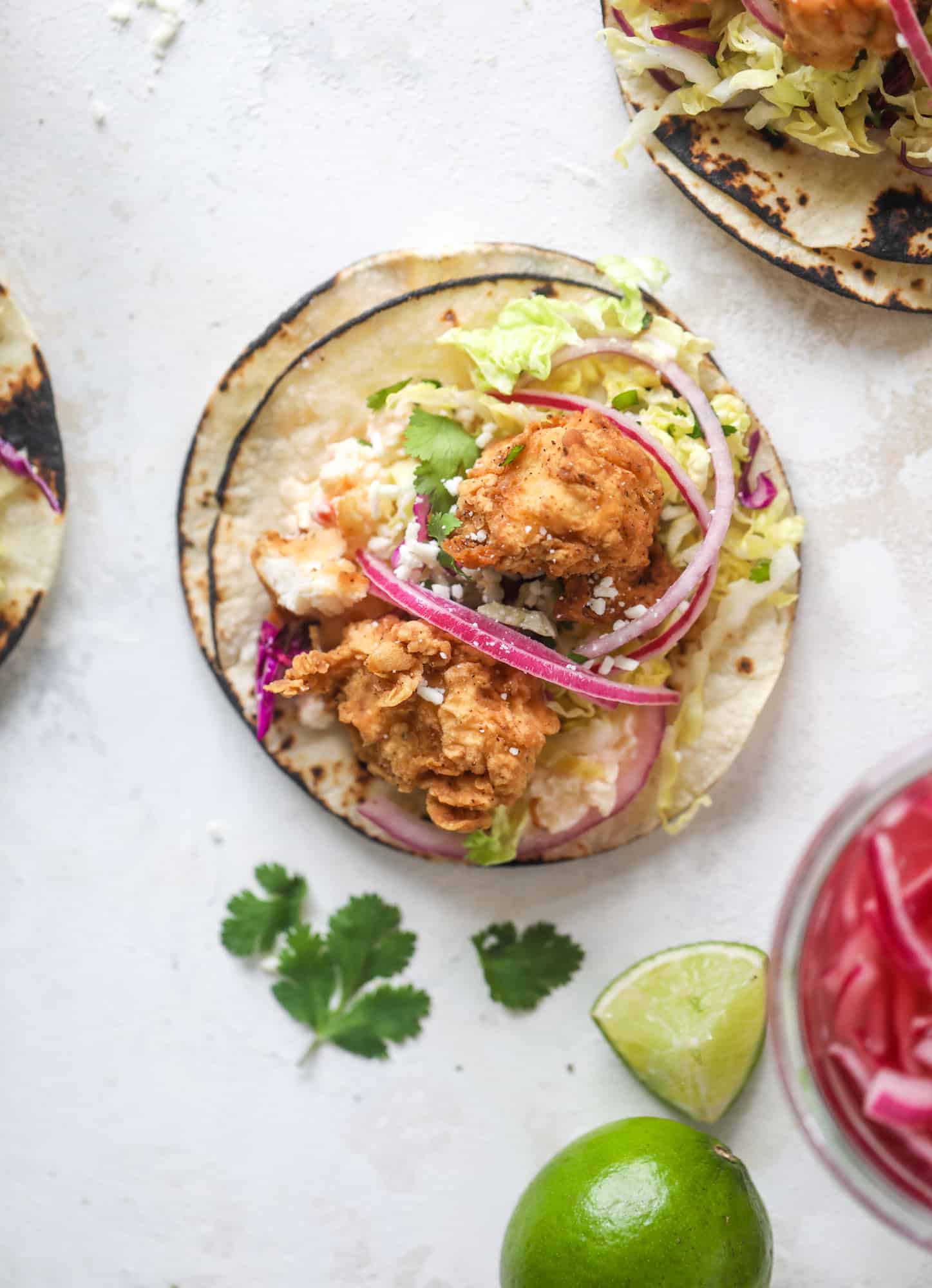 Taking crispy chicken tacos to the next level by wrapping them in a warm tortilla with gouda pimento cheese, lime cabbage and pickled onions!