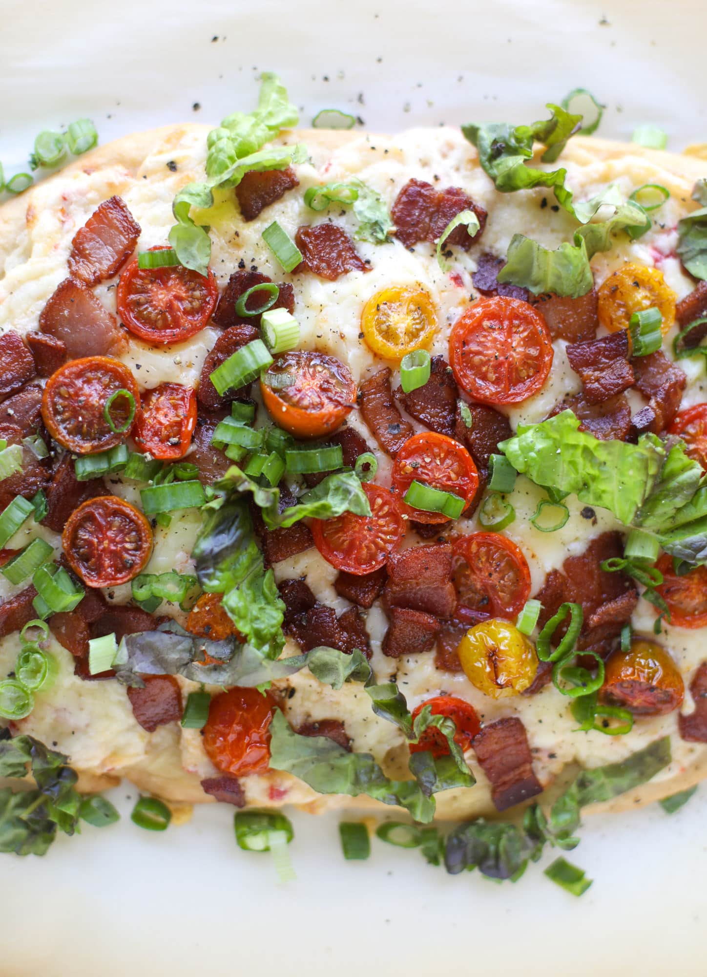 A crisped flatbread crust is topped with creamy pimento cheese, crispy bacon, garlic burst tomatoes and shredded lettuce. It's a flavor explosion!