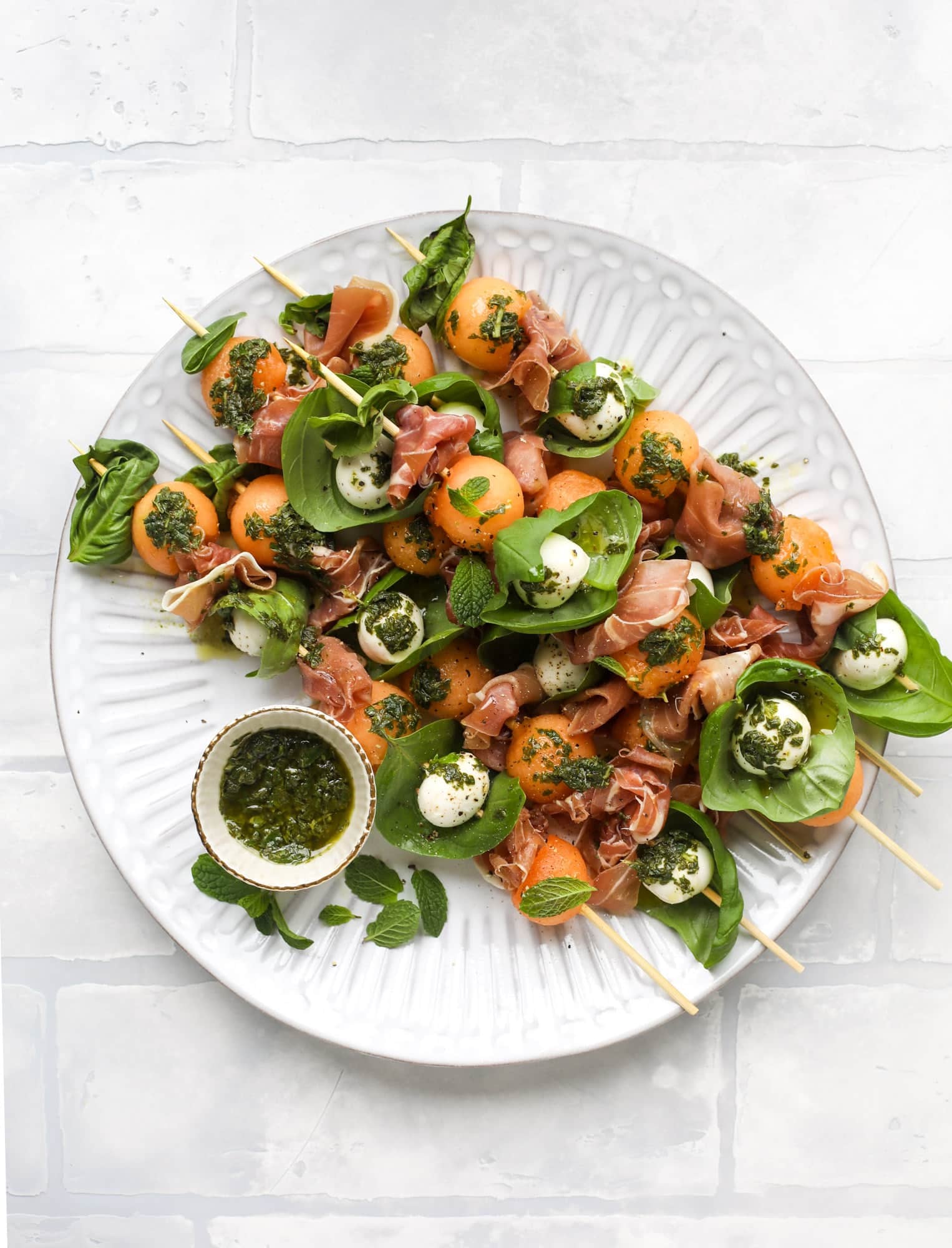 These cantaloupe prosciutto skewers are the perfect cantoloupe caprese snack! Salty prosciutto, sweet melon and fresh mozzarella drizzled with mint pesto!