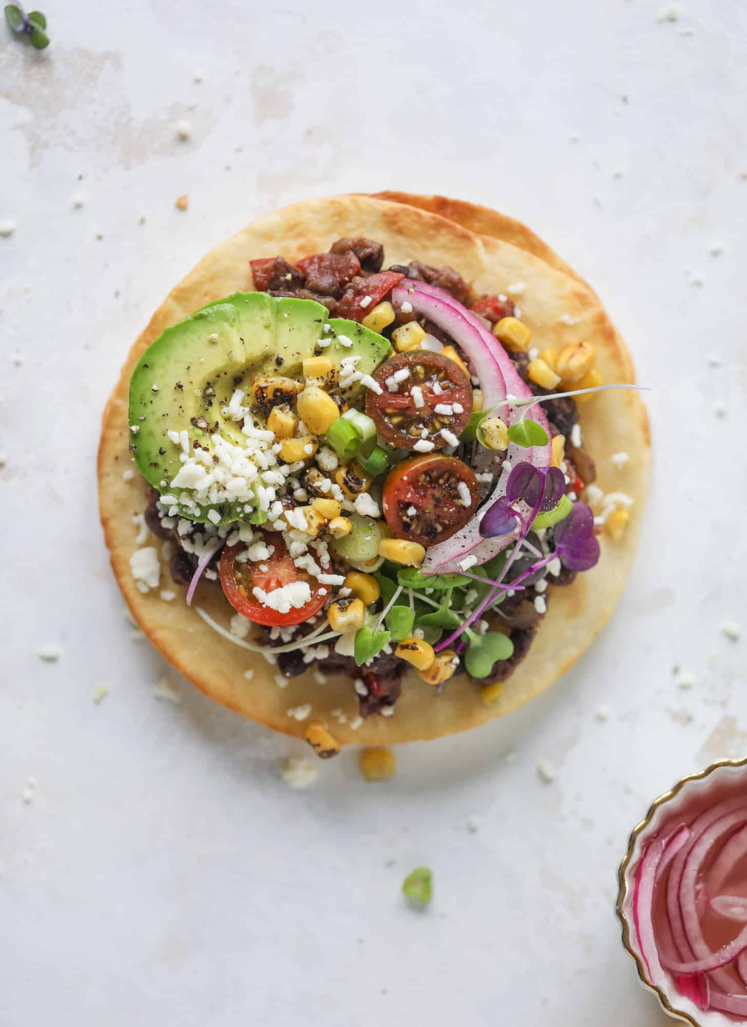 These saucy black bean tostadas are super flavorful and easy for a weeknight meal. Crunchy tortillas topped with beans and tons of veggies. Delish!
