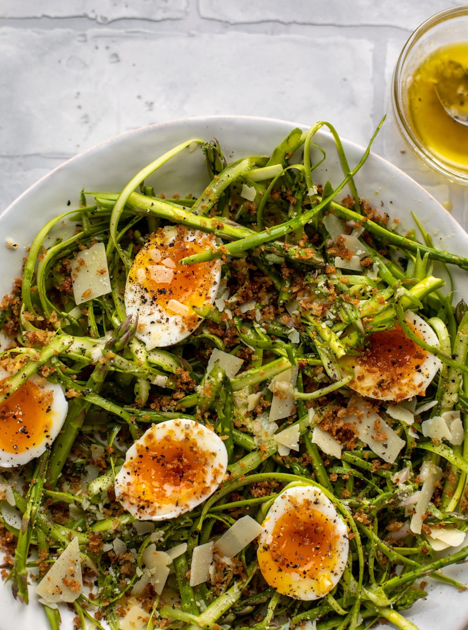 This shaved asparagus salad is tossed with a delicious parmesan vinaigrette, then topped with soft boiled eggs and finished with crunchy garlic breadcrumbs!