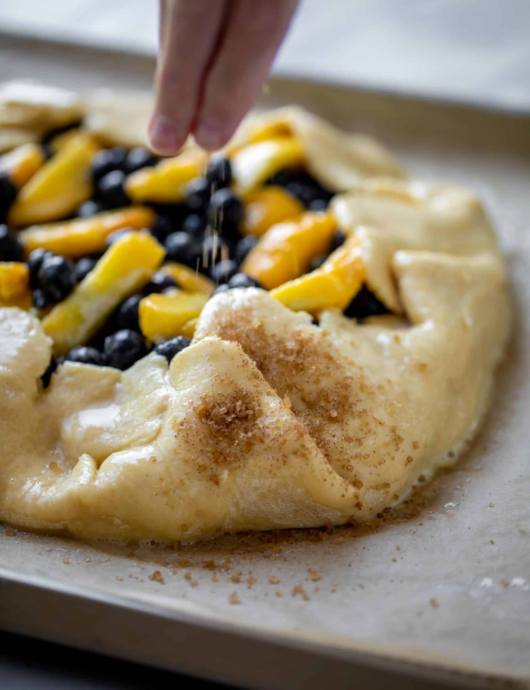 sprinkling cinnamon sugar on dough