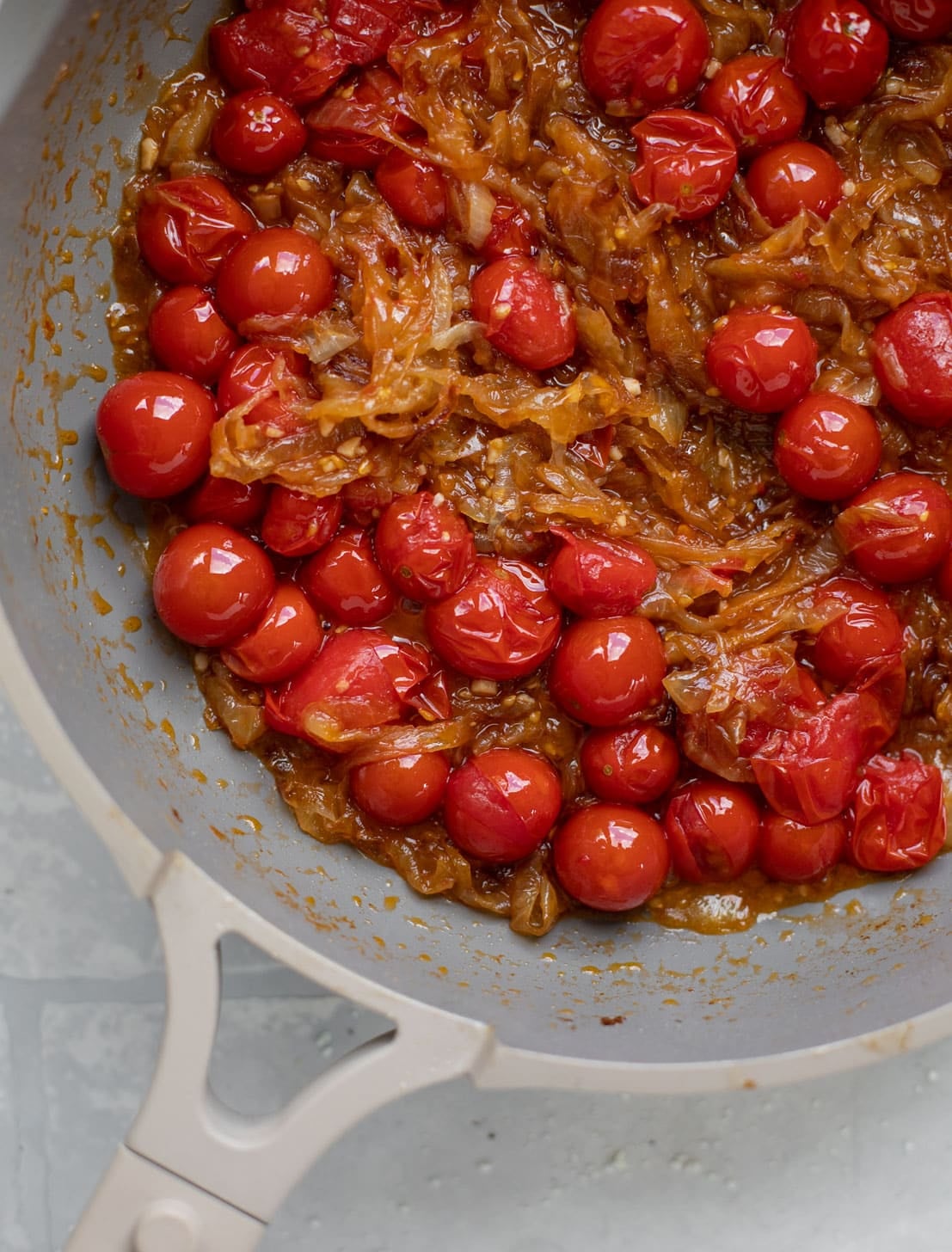 caramelized onions and burst cherry tomatoes in a skillet
