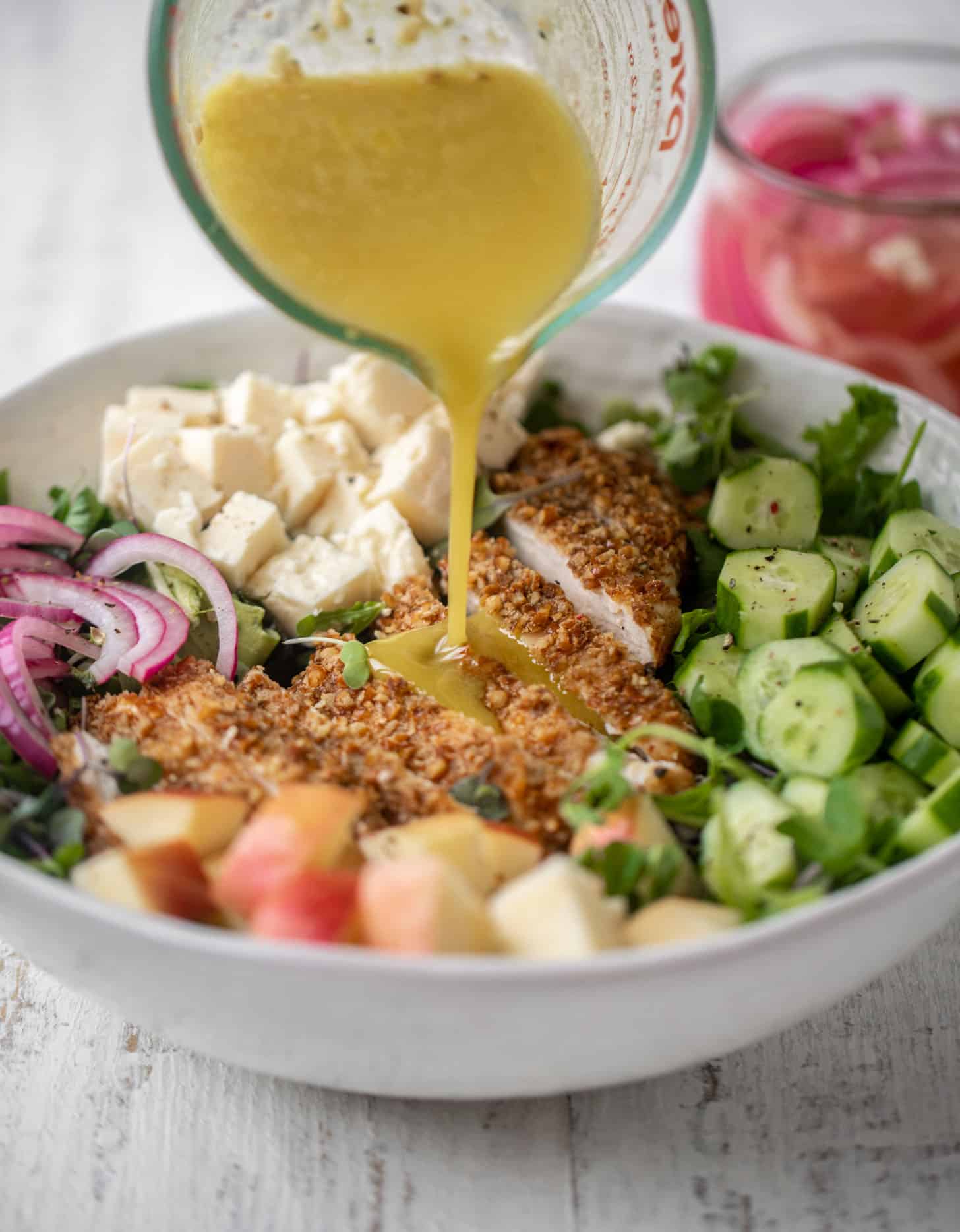 pouring dressing on pretzel crusted chicken salad