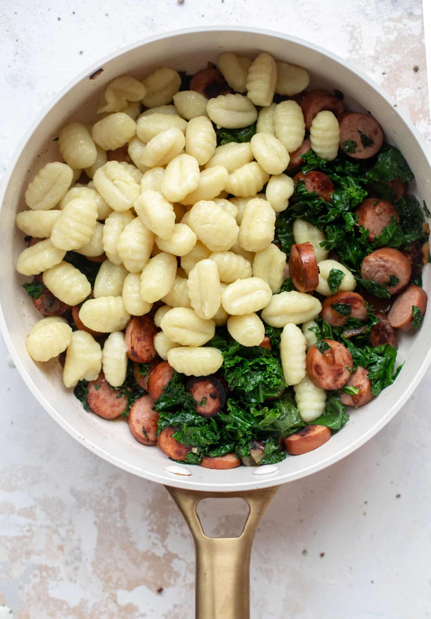preparing smoked sausage and kale gnocchi skillet