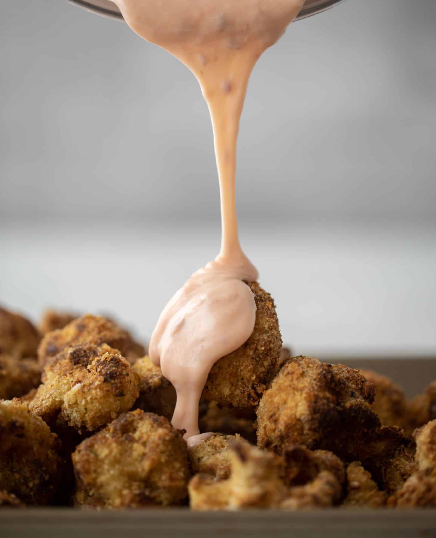 pouring bang bang sauce on cauliflower