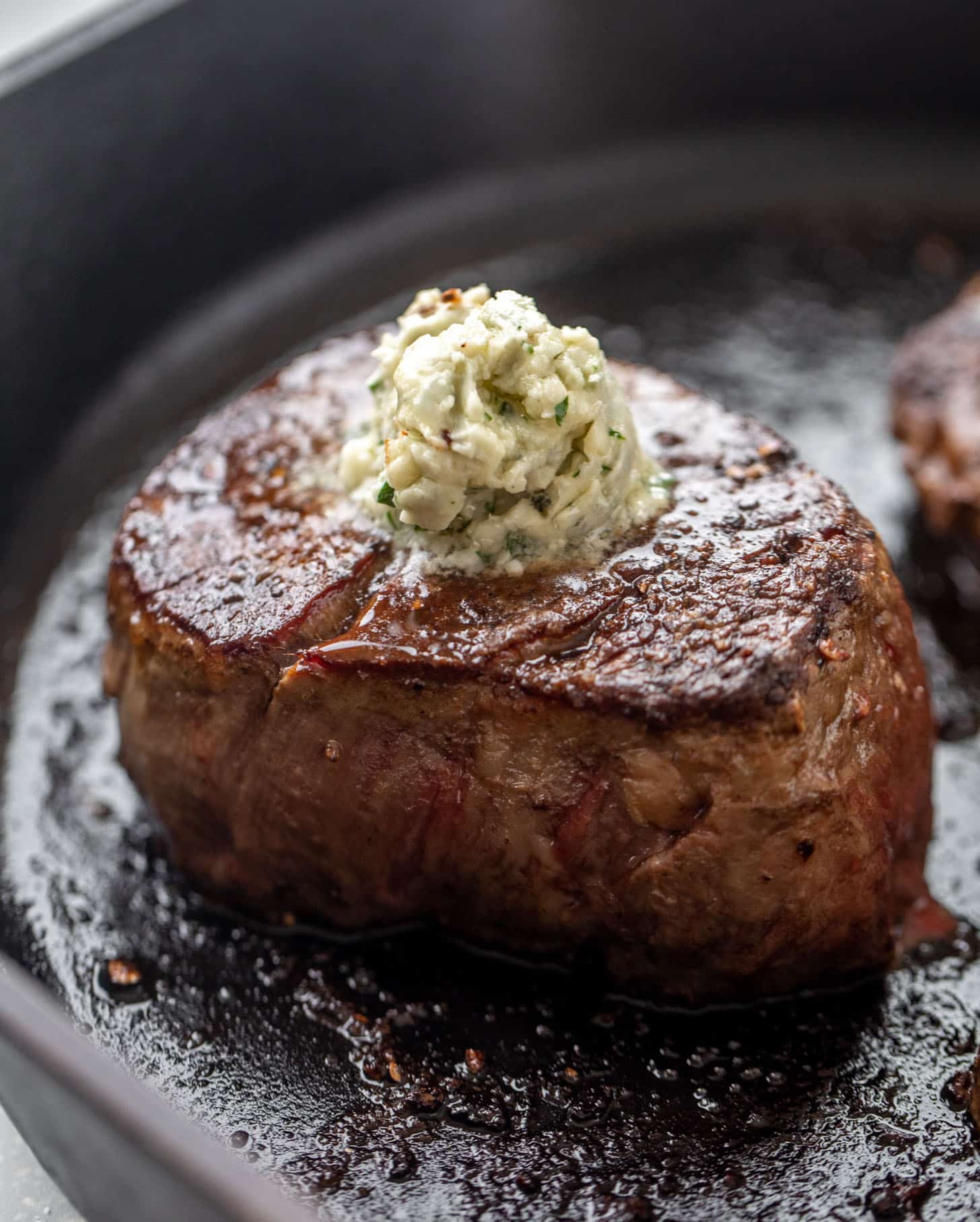 seared steak in a cast iron skillet with blue cheese butter