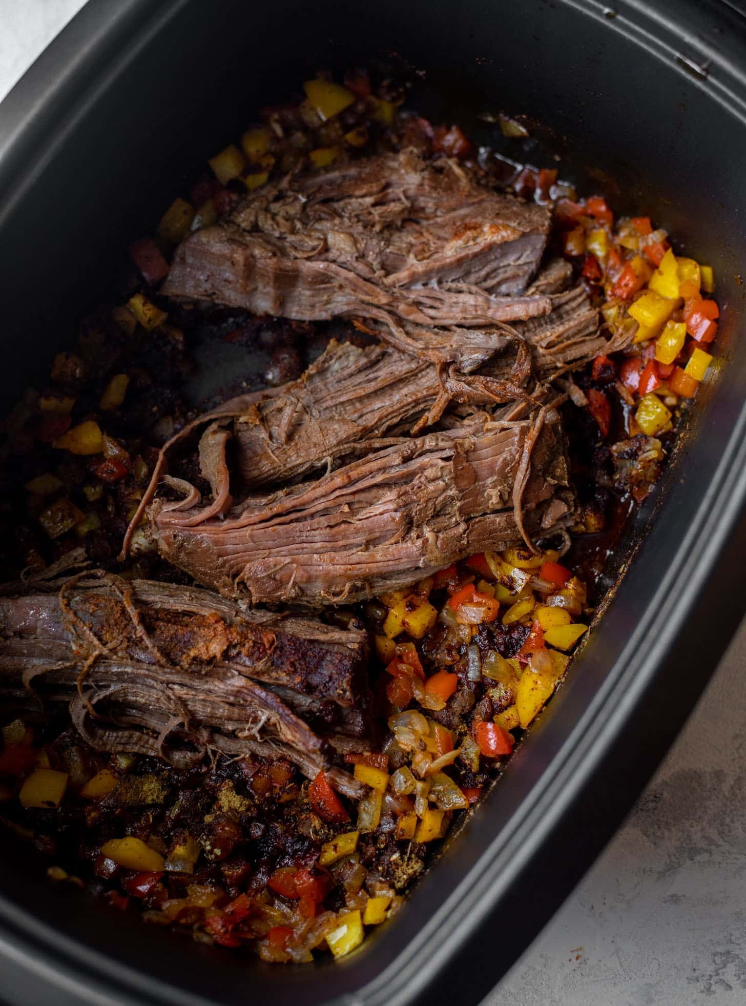 slow cooker with brisket and peppers and onions